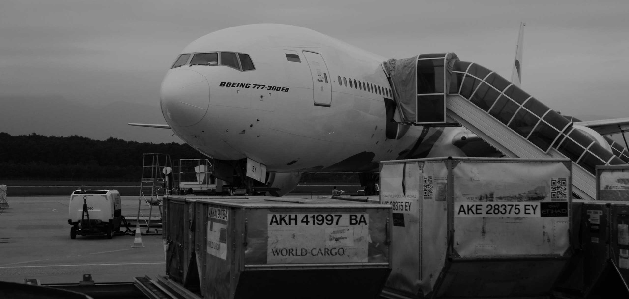 Two cargo containers in front of an aircraft boeing 777 300 ER that is waiting in the airport tarmac.
