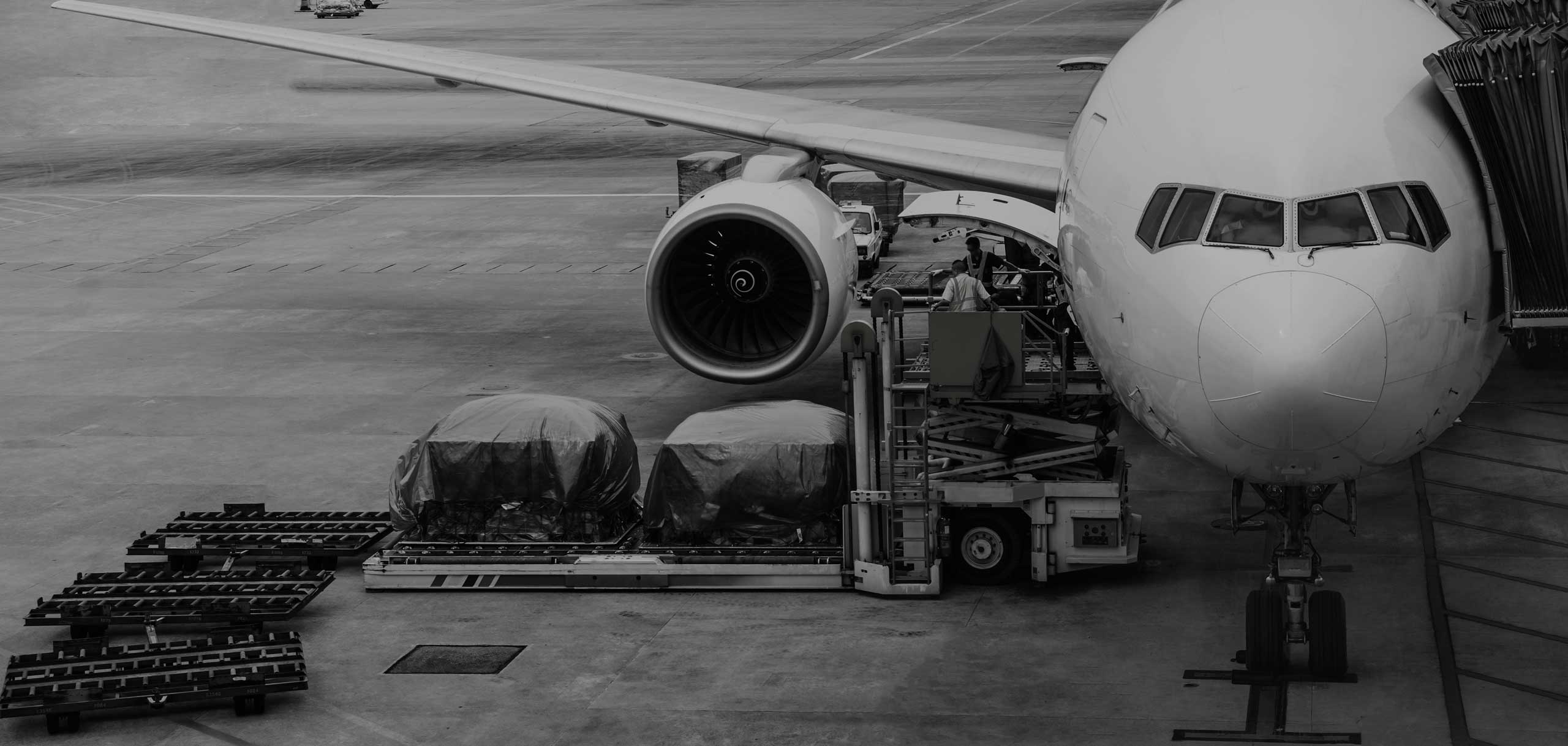 Container Loader Ground Support Equipment (GSE) supporting the cargo good loading operations of two containers and pallets of an aircraft on the ground of the airport tarmac from the right side.